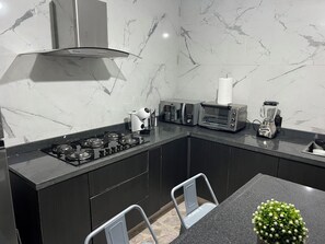 Eine moderne Küche mit Gaskochfeld, Toaster, Mixer und einer kleinen Topfpflanze.
