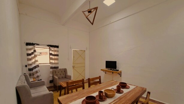 A dining area with a wooden table, chairs, and a TV mounted on a wall.