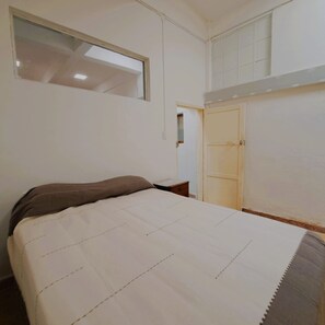 Un dormitorio con cama, ventana y armario.