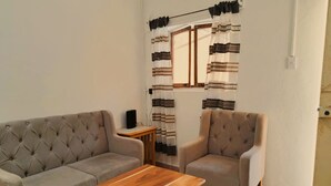 A living room with a grey sofa, a matching armchair, and a wooden coffee table.
