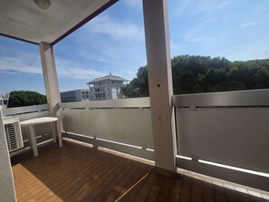 An outdoor balcony with a wooden floor, white railing, and a table. - Holiday apartment with air conditioning (Bibione)