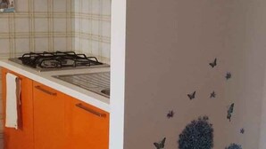 Een keuken met oranje kastjes, een gasfornuis en een decoratieve wand met een lijstwerkfoto.