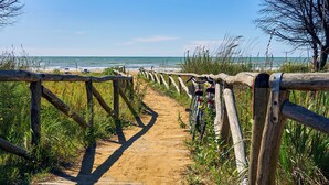 Een houten pad dat naar een strand leidt, met een fiets ernaast geparkeerd.