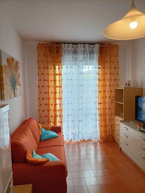 Ein Wohnzimmer mit einer Couch, einem Fernseher und einem Schrank.