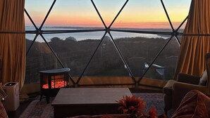 Una habitación acogedora con un ventanal grande, una pequeña mesa con fuego y una zona de estar cómoda.