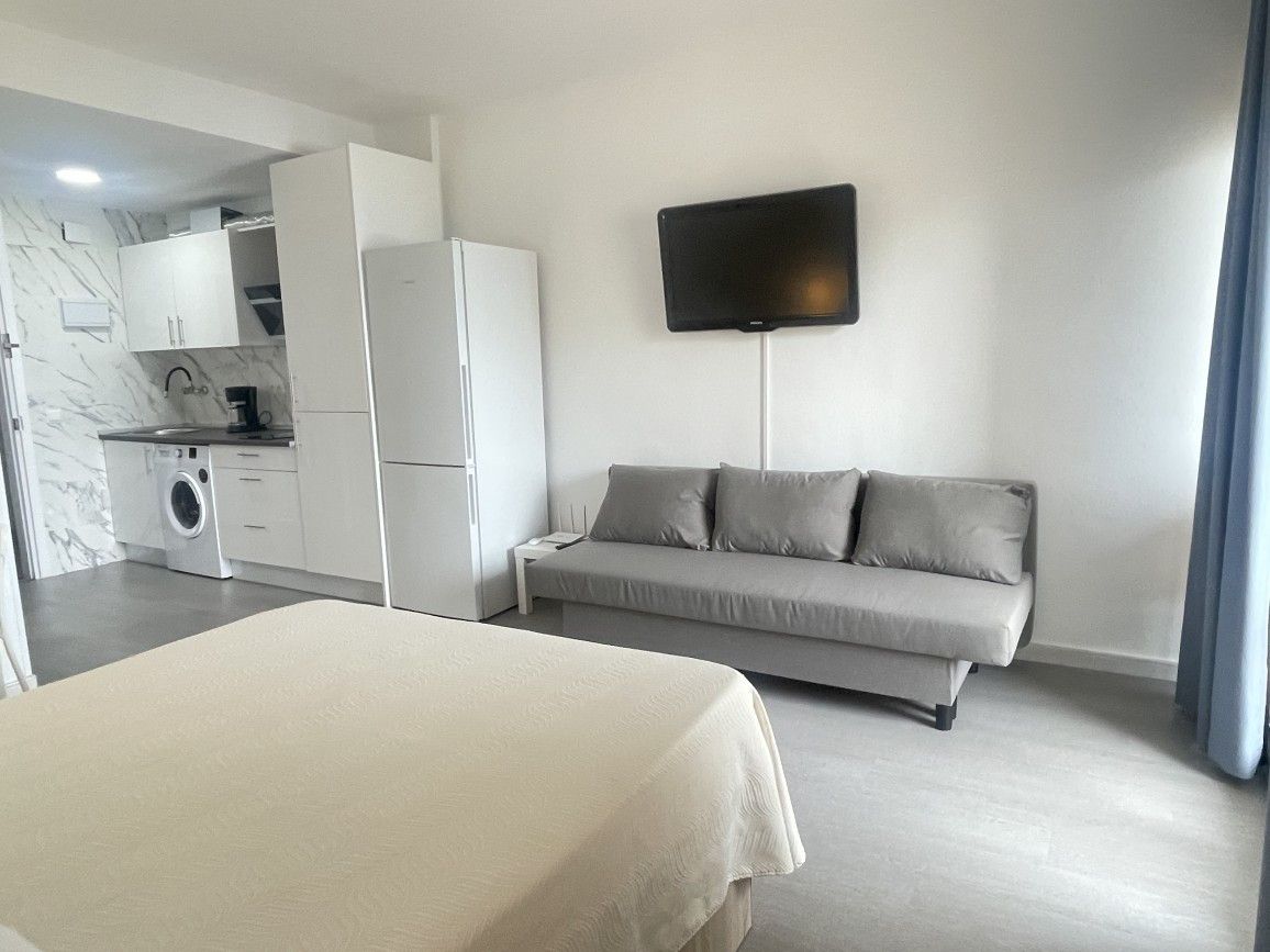Une chambre d’hôtel moderne équipée d’un lit, d’un canapé, d’un téléviseur à écran plat, d’un lave-linge et d’un coin cuisine.