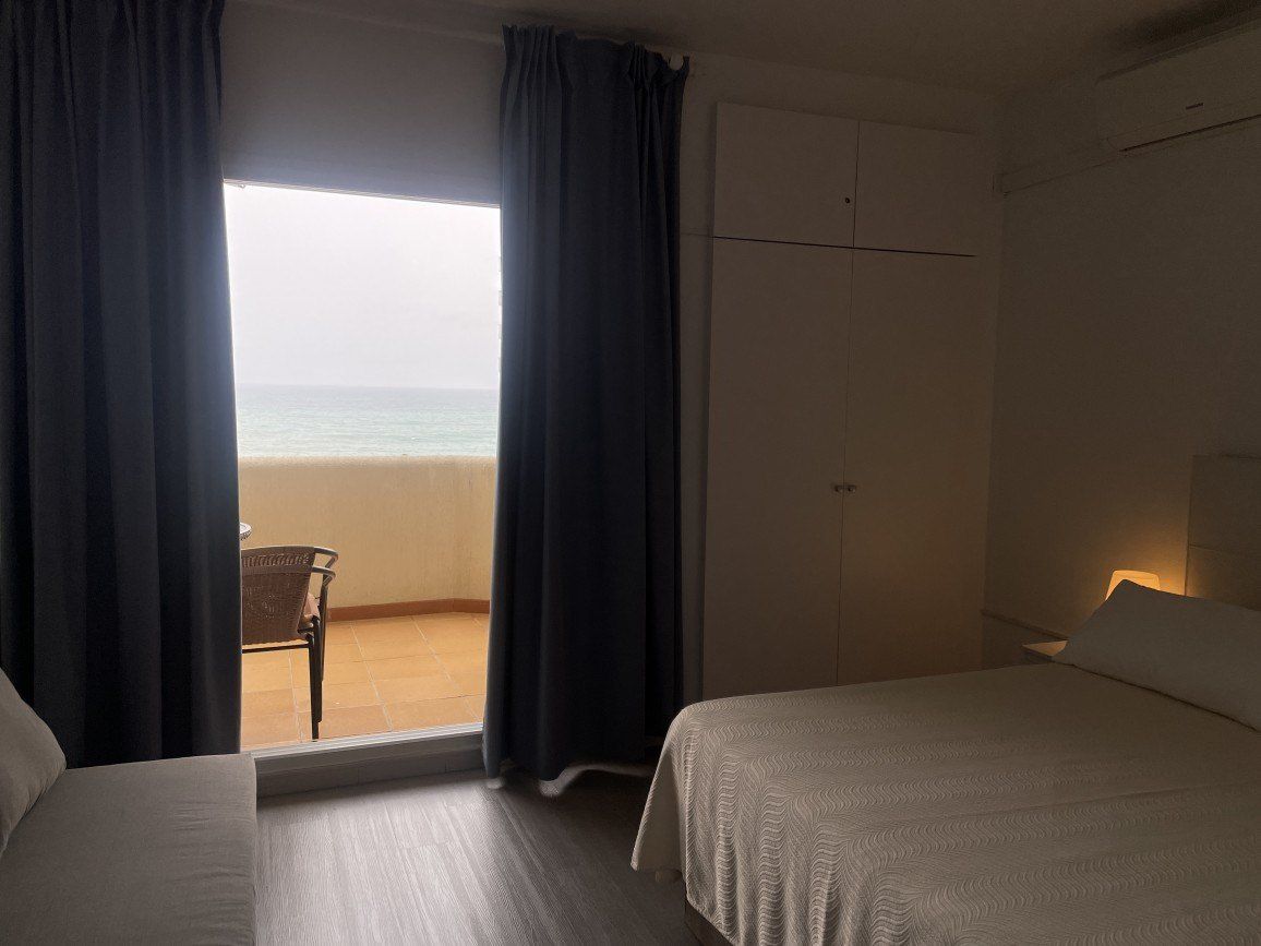 Een hotelkamer met een bed, een stoel en uitzicht op het strand.