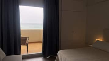Een hotelkamer met een bed, een stoel en uitzicht op het strand.
