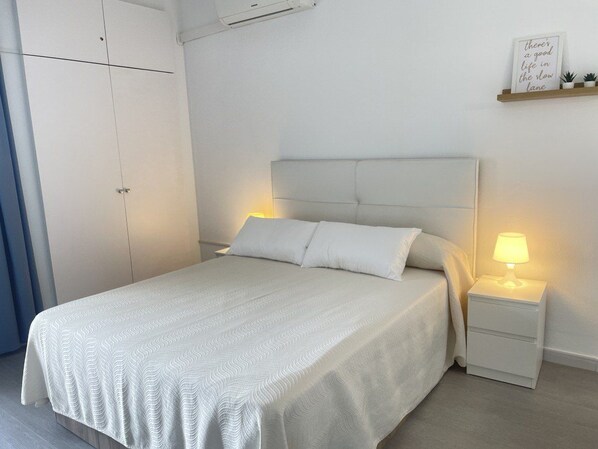 A bedroom with a bed, bedside tables, a wall-mounted shelf with a sign, and a wardrobe.
