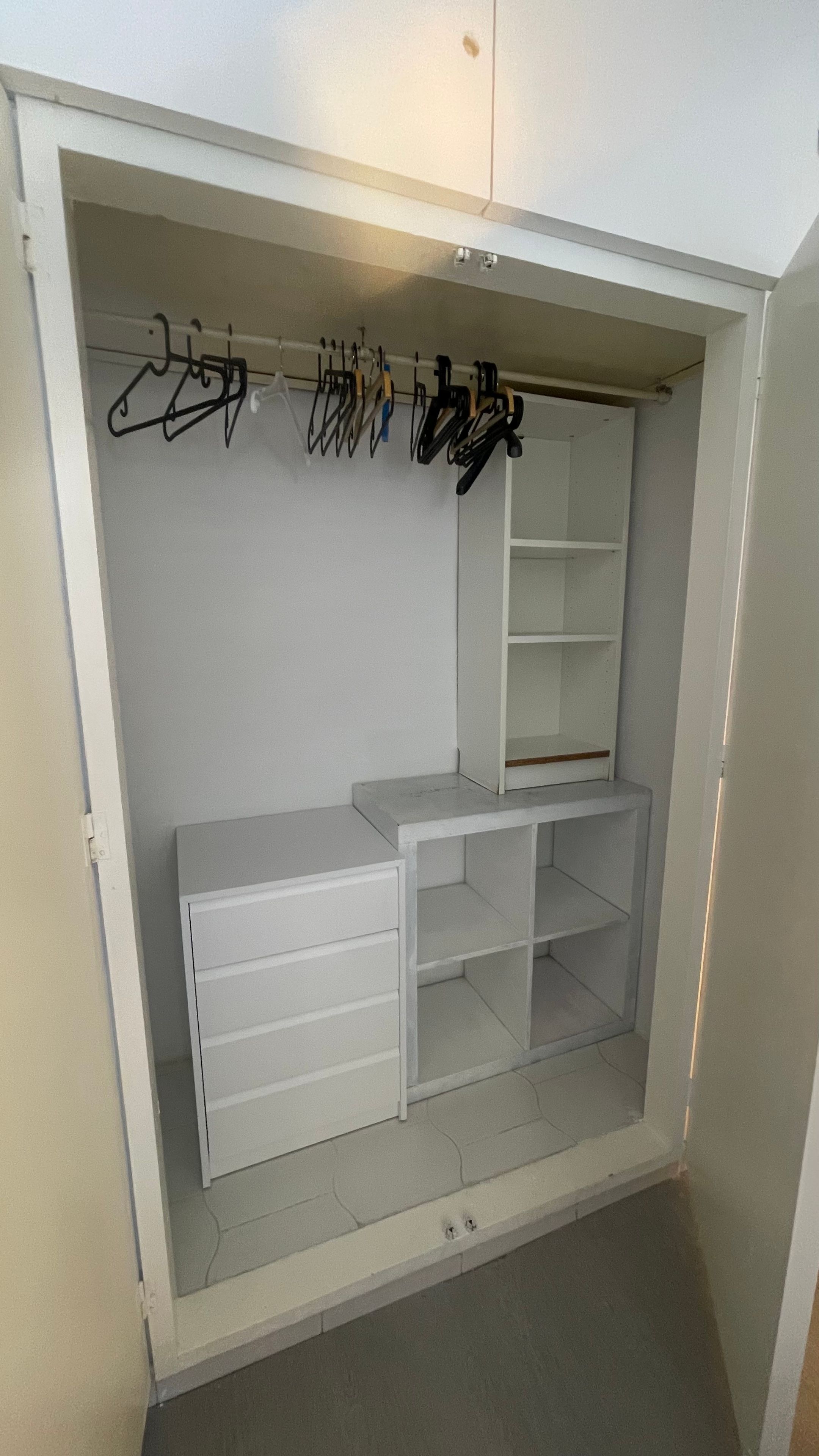 Een inloopkast met open planken, een kledingroede en een ingebouwde bank.