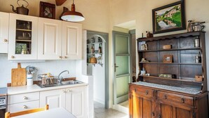 A kitchen with white cabinets, a wooden countertop, a hanging light fixture, and a wooden cabinet with shelves. - Cozy Cottage Retreat in Berzi (Berzi)