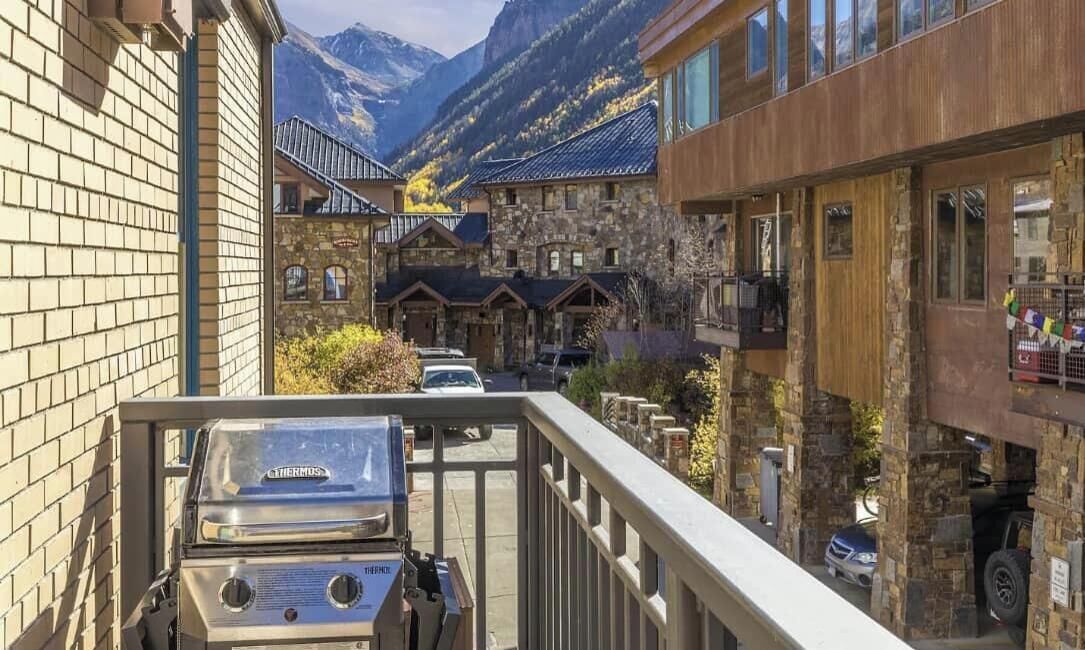 Un chalet de montagne avec des bâtiments en pierre, un barbecue et une vue sur les montagnes.