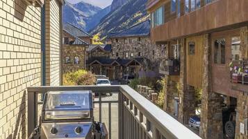 Un chalet de montagne avec des bâtiments en pierre, un barbecue et une vue sur les montagnes.