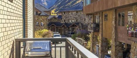 A mountain lodge with stone buildings, a barbecue grill, and a view of the mountains.