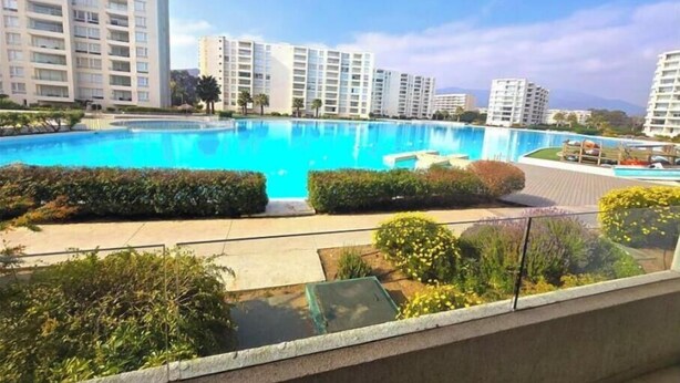 A large swimming pool surrounded by greenery and modern buildings.