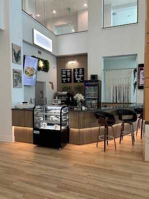 Ein modernes Bistro-Café mit Holztresen, Speisekarten und einer Sitzgegend mit Stühlen.
