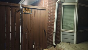 Una cancelada de madera con un letrero de advertencia, un muro de ladrillo y una ventana con persianas.