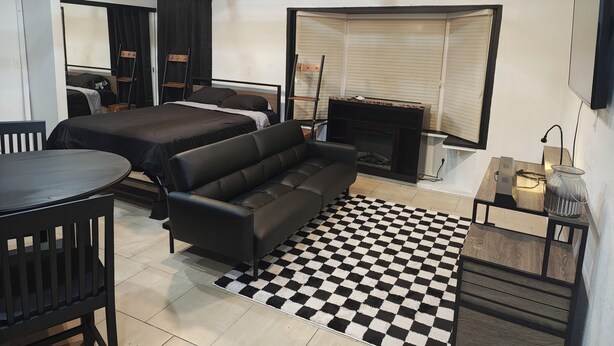 Una habitación moderna con cama, sofá, mesa y chimenea.