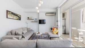 Una sala de estar moderna con un sofá, un televisor y un amplio ventanal.