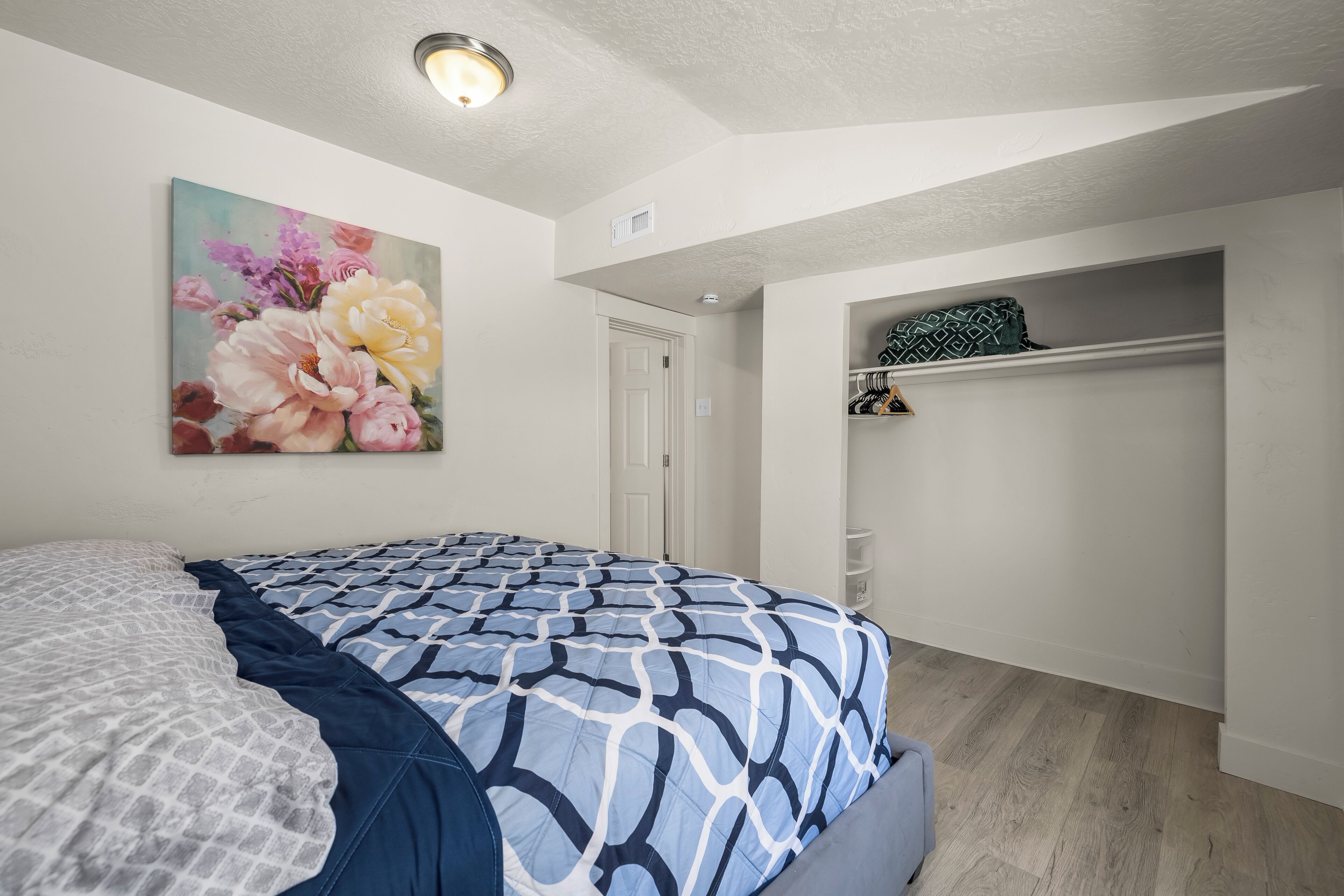 Quarto com cama, armário e uma pintura na parede.