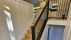 A staircase with wooden steps and black railings, leading to a landing with a kitchen area. - Halfmoon Bay Hideaway Top Suite (Halfmoon Bay)
