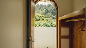 An open door with a view of a lush garden and a wooden interior. - Garden Hill Kintamani Natural Hot Spring (Kintamani)