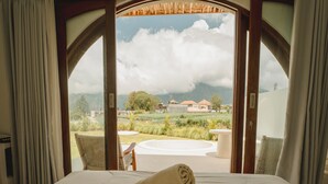 A bed with a view of a landscaped area and mountains. - Garden Hill Kintamani Natural Hot Spring (Kintamani)