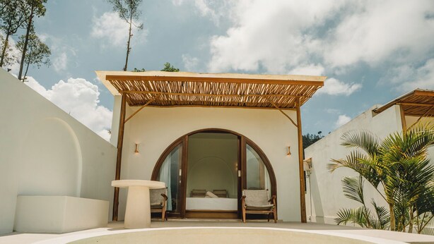 A spa area with a hot tub, a covered seating area, and a bedroom with a large window. - Garden Hill Kintamani Natural Hot Spring (Kintamani)