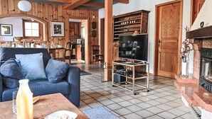 Ein gemütliches Wohnzimmer mit Sofa, Fernseher und Kamin.