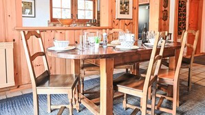 Ein Esszimmer mit Holzboden und einem großen Esstisch, gedeckt für sechs Personen, umgeben von sechs Stühlen.
