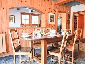 Ein Esszimmer mit Holzboden und einem großen Esstisch, gedeckt für sechs Personen, umgeben von sechs Stühlen.