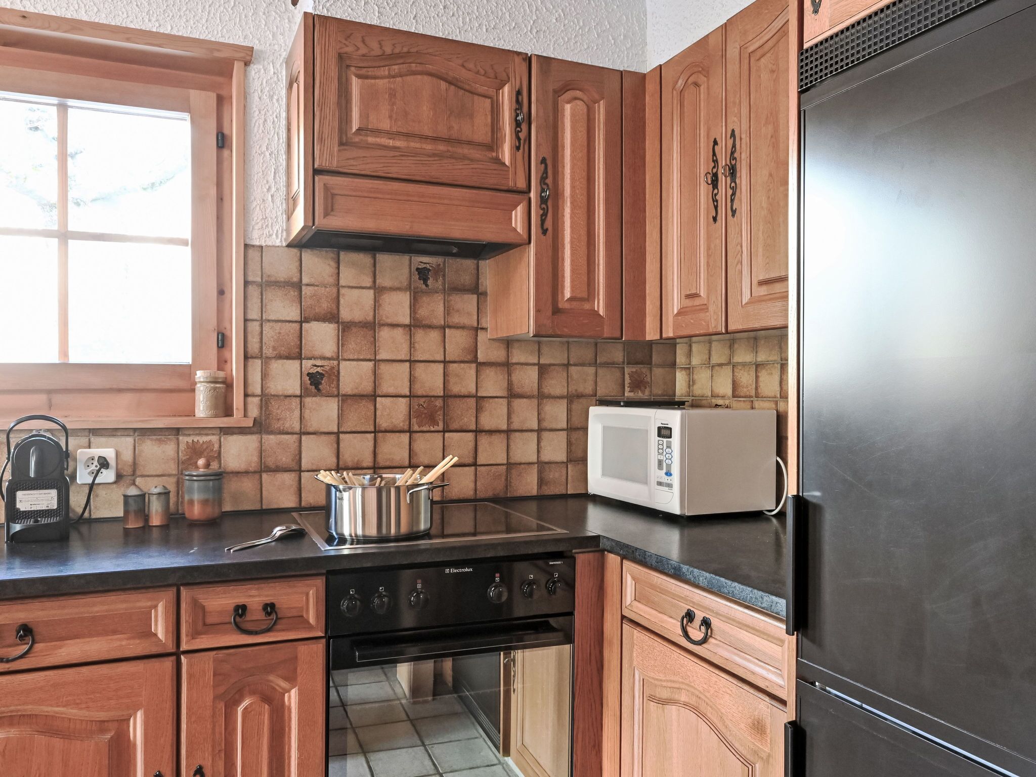 A kitchen with wooden cabinets, a microwave, a stove, and a refrigerator.