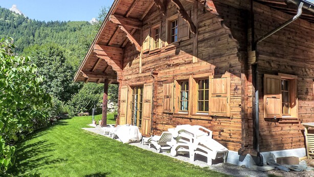 Eine Holzhütte mit geneigtem Dach, großen Fenstern und einer Veranda.