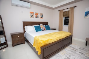A bedroom with a bed, nightstand, dresser, and a window with curtains. - Ultimate Blue Mountain CityView Rooftop Pool Condo (Kingston)