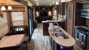 A compact kitchen with a central island, built-in appliances, and a dining area with a table and chairs. - Cozy Backyard RV in Apopka/Orlando FL with AC (Apopka)