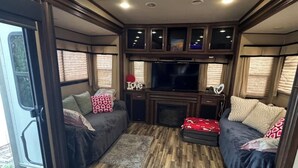A cozy RV interior with a seating area, a fireplace, and a television. - Cozy Backyard RV in Apopka/Orlando FL with AC (Apopka)
