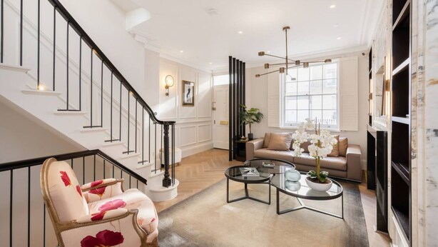 A spacious living room with a staircase, a sofa, a coffee table, and a fireplace. - Belgravia 4-bed House With Private Garden (London)