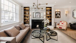 A living room with a sofa, a fireplace, a coffee table, and a chair. - Belgravia 4-bed House With Private Garden (London)