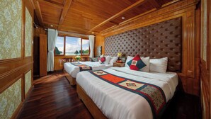 Una habitación con una cama grande, dos camas más pequeñas, piso de madera, un ventanal con vistas y techo de madera.