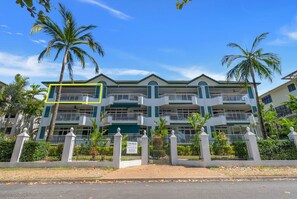 Un hotel de varios pisos con balcones, palmeras y un cielo despejado.