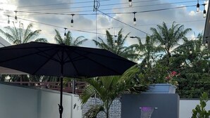 Une piscine agrémentée d’un élément décoratif aquatique, entourée de palmiers et bordée d’un mur orné de motifs.
