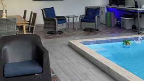 Un espace piscine intérieure doté de ventilateurs de plafond, d’un téléviseur et de chaises longues.