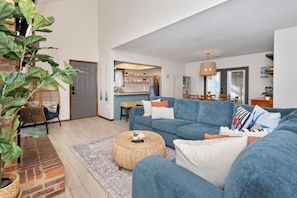A living room with a blue sofa, a round coffee table, and a potted plant. - Steps to Beach 3BR Coastal Retreat Sleeps 10 (North Myrtle Beach)