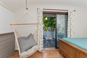 A room with a bed, a hanging chair, a small table, and a sliding glass door leading to an outdoor area. - Steps to Beach 3BR Coastal Retreat Sleeps 10 (North Myrtle Beach)