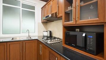Une cuisine avec des meubles de rangement en bois, un évier en acier inoxydable, une cuisinière et un micro-ondes noir.