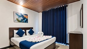 A hotel room with a bed, a painting on the wall, a blue curtain, and a wooden headboard. - The Lakeside Stay (Nuwara Eliya)
