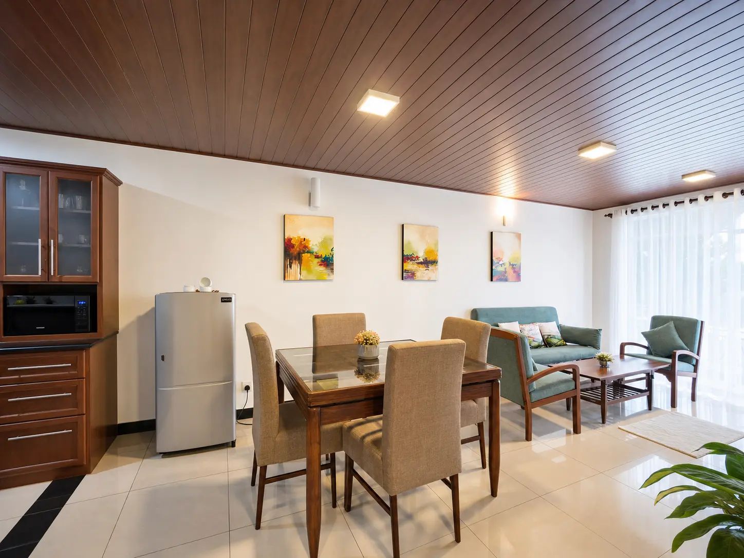 A modern living room with a dining area, wooden ceiling, and artwork on the wall.