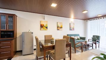 Un salon moderne avec un coin repas, un plafond en bois et des œuvres d’art accrochées au mur.