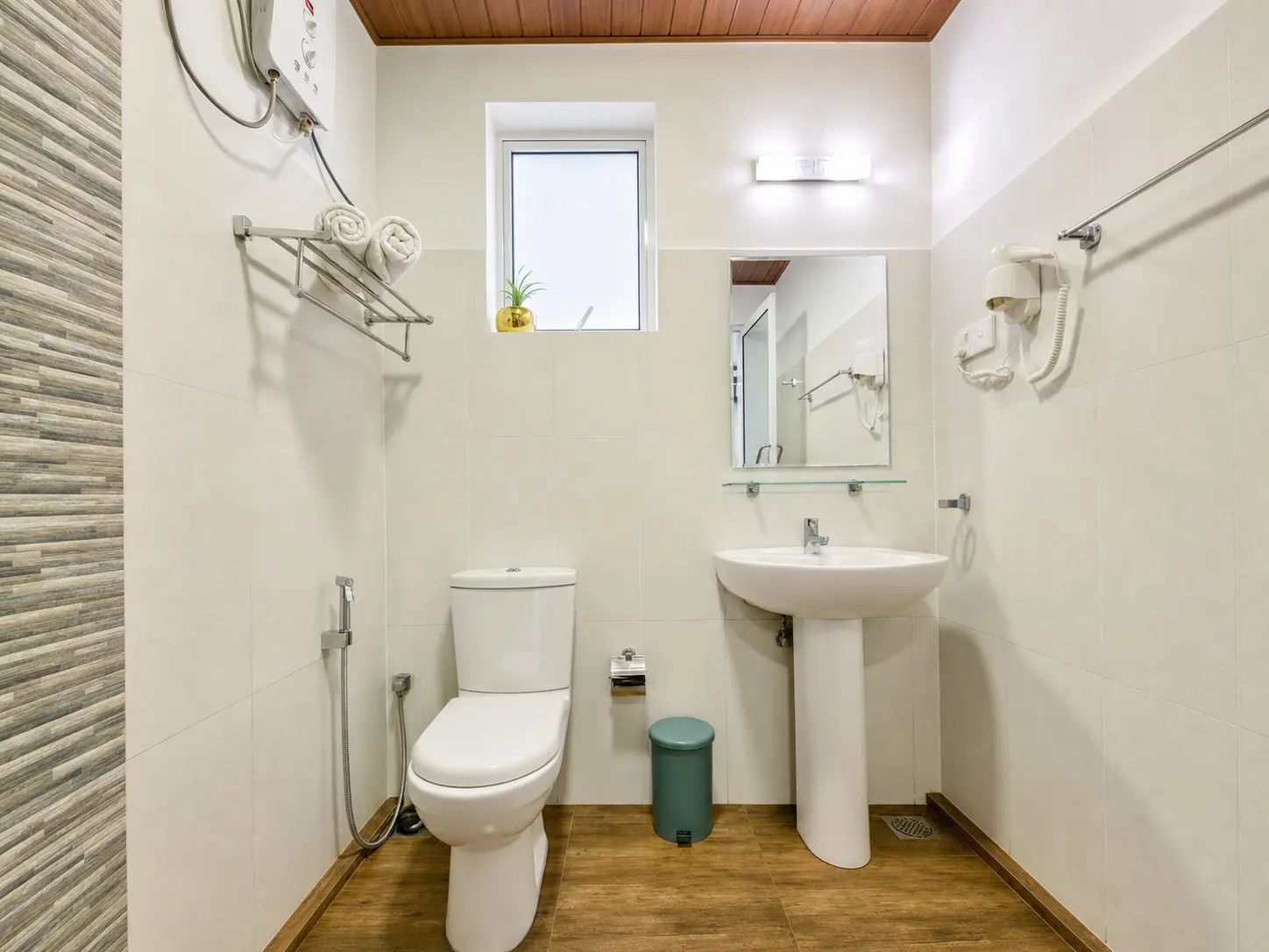 Un baño pequeño con inodoro, lavamanos y un ventanal.