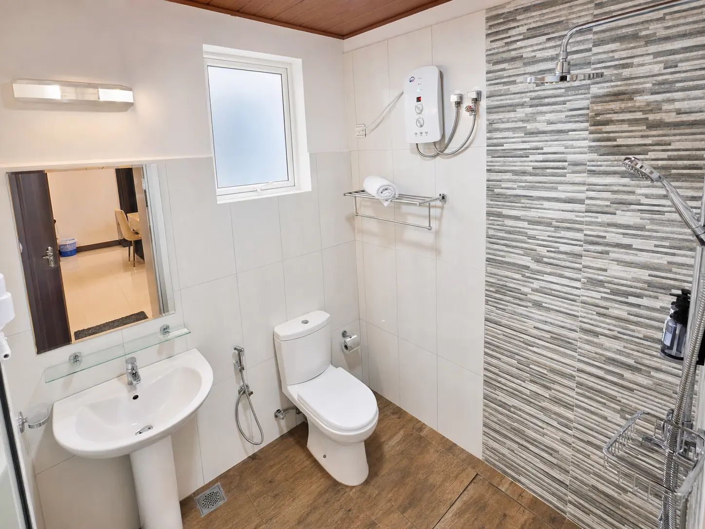 A bathroom with a toilet, two sinks, a shower, and a window.